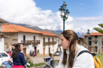 Profile of a young latina woman sitting in a square in a downtown