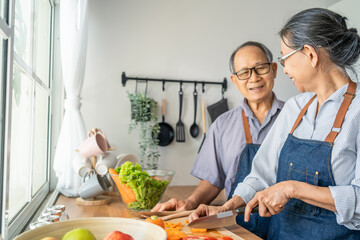 Asian loving senior elderly couple wear apron and cooking in kitchen. 