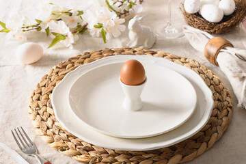 Spring Easter festive table setting with organic brown egg, white bunny and blossom flowers of natural materials. Close up.