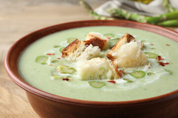 Delicious asparagus soup with croutons in bowl on table, closeup