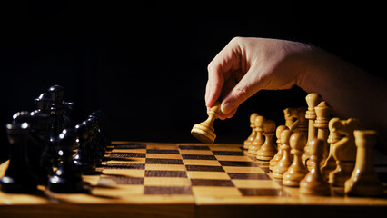 A man hand with a chess piece in a board game. Opening of the chess game with the move of the white...