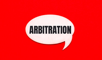 On a bright red background, a light wooden curly card with the text ARBITRATION