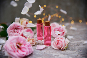 a bottle of rose oil on a background of rose flowers and bokeh