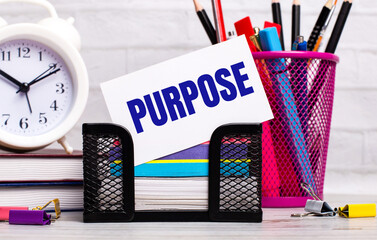The office desk has diaries, an alarm clock, stationery, and a white card with the text PURPOSE....