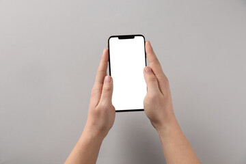 Man with smartphone on grey background, top view