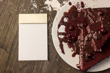 Notepad, cranberry cake, hot chocolate on the cake, powdered sugar.