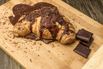Croissant with chocolate on a wooden board