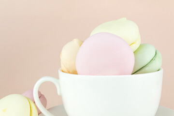 French delicate marshmallows dessert for Breakfast in porcelain white coffee cup mug on pastel beige background.