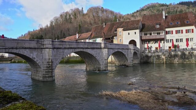 Medieval town Saint-Ursanne, Canton Jura, with beautiful facades of historic houses and stone bridge over river Doubs. Movie shot February 7th, 2022, Saint-Ursanne, Switzerland.