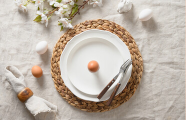 Fototapeta na wymiar Spring Easter festive table setting with organic brown egg, white bunny and blossom flowers of natural materials. View from above.