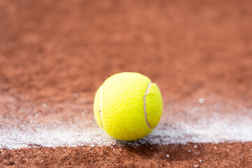 Tennis ball on white line on clay court close up. Sports tournament competition, in or out concepts
