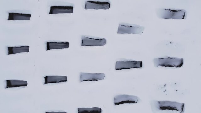 Open empty graves among the snowy field, aerial drone view of emty tombs in the winter
