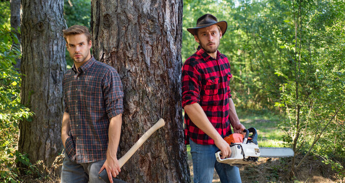 Man with axe in forest. Lumberjack woodcutter in a plaid shirt. Lumberjack brutal bearded man.