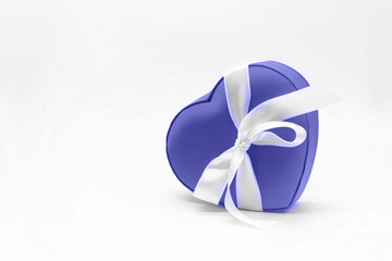 Heart shape gift box Pantone color very peri with bow. White background. Copy space. Concept of love