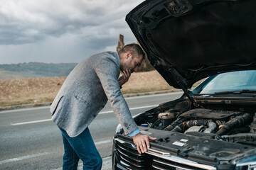 Elegant middle age business man calling towing service for help on the road. Roadside assistance...