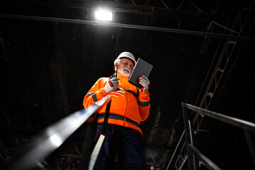 Professional heavy industry engineer worker wearing safety uniform and hard hat, using tablet...