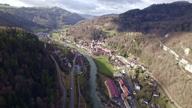 Medieval town Saint-Ursanne, Canton Jura, with beautiful facades of historic houses and river Doubs in the foreground. Movie shot February 7th, 2022, Saint-Ursanne, Switzerland.