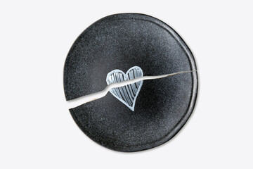 Broken ceramic plate with a painted heart isolated on a white background