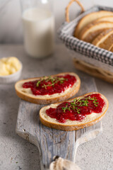 White bread slices with butter and raspberry jam on it, greens on wooden board, organic country sweet sandwich, homemade dessert. Copy space.