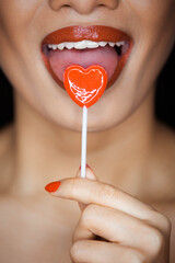 Valentine's day concept: An attractive young Asian woman eating heart candy. A woman with sexy lips...