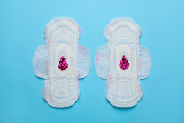 Menstrual pads with drops made of pink sequins on light blue background, flat lay