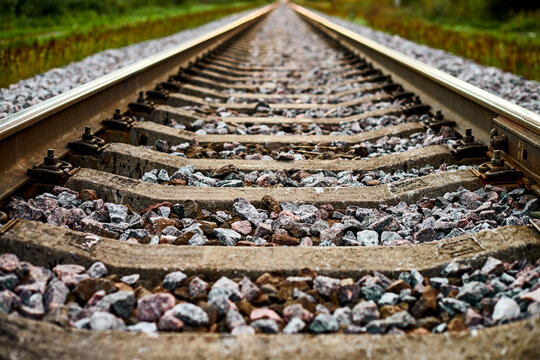 Railway track line going into distance, railroad train track with crushed stone, two parallel rails