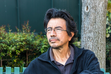 portrait of a mature hispanic man looking away from the camera, at the park