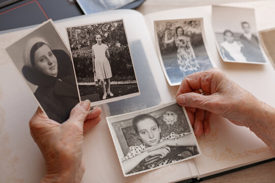 Old hands. Senior woman is looking her own photos were taken in 1955 ,1957,1967. Retired person has got smile while remembering how young she was. Selective focus. 