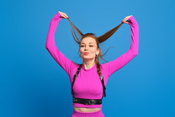 Fototapeta na wymiar Happy woman in purple knitted suit playing with hair over blue background