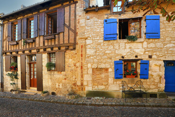 Fototapeta na wymiar Facade of stone houses with wooden doors and blue windows in Bergerac town, France