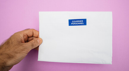 Man hand holding envelope with Courrier Personnel Personal Mail sign sticker