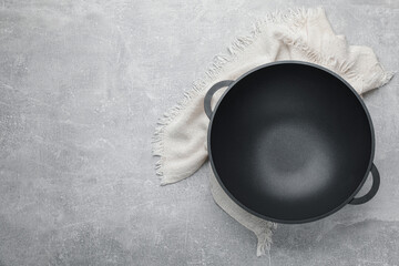 Empty iron wok and towel on grey table, top view. Space for text - obrazy, fototapety, plakaty