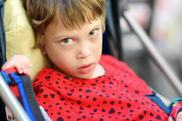 Portrait of a cute little disabled girl in a wheelchair. On her arms orthosis. Child cerebral...