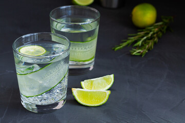 Cucumber water with lime and rosemary. glass of Homemade flavoured lemonade on the black table. detox water. cold summer lemonade with copy space.