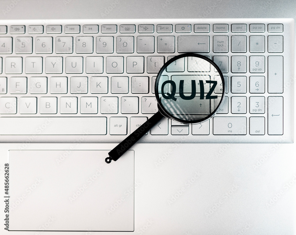 Poster quiz word through magnifying lens on laptops keyboard.