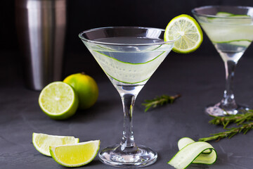 martini with lime.Cucumber water with lime. martini glass of lemonade with slices of lime and cucumber on the black table. cold alcohol drinks with copy space.