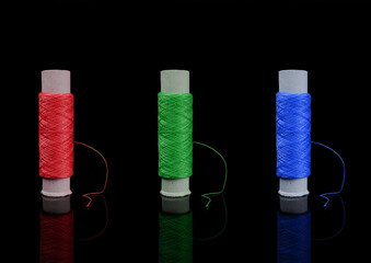 A skein of thread, a spool of thread for sewing, on a black background isolated with reflection