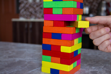 Fototapeta na wymiar Playing wooden tower game with colorful blocks.