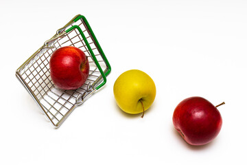 apples rolled out of a metal grocery basket on a white background