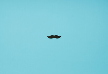 Blue background with a black paper mustache in the middle.