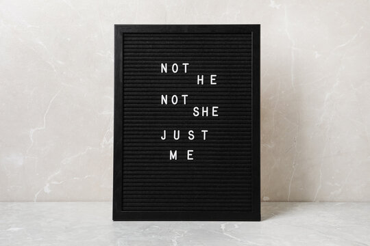 Black board with text Not He Not She Just Me on light grey marble table. Gender identity