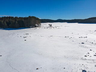 Aerial winter view of Shiroka polyana Reservoir covered with ice, Bulgaria