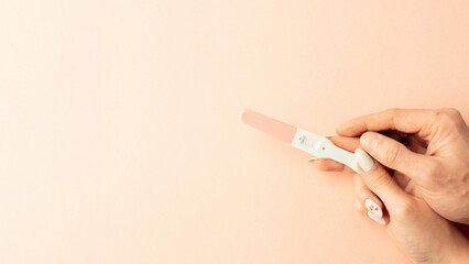 Pregnancy test kit. Female hand hold positive pregnant test with silk ribbon on pink background. Medical healthcare gynecological, pregnancy fertility maternity people concept.