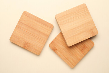 Stylish wooden cup coasters on beige background, flat lay