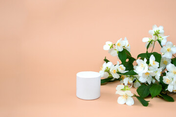 White podium for displaying cosmetics and various products on a beige background with jasmine,...
