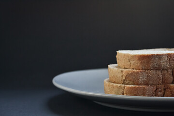 Three slices of homemade bread were placed on a grey plate on a black background
