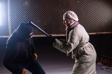 Girl strikes robber with bat. Self defense concept