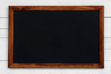 Fototapeta na wymiar Clean black chalkboard hanging on white wooden wall