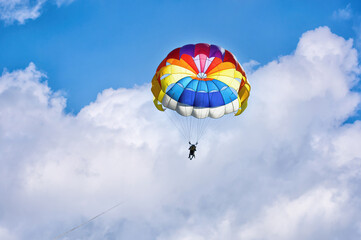 Paragliding using a parachute on background of blue cloudy sky.