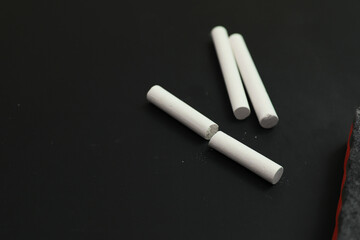 Pieces of white chalk and duster on black board, space for text